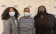 Three Arc/Morris staff wearing masks stand in front of a white banner with the Arc/Morris logo at the Years of Service event.