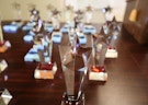 A closeup of a collection of glass, star-shaped Arc/Morris awards displayed on a wooden table.