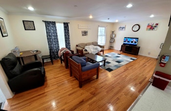 A living room at Arc/Morris Chatham Group Home featuring shiny hardwood floors, an area rug, flat screen TV and comfortable seating