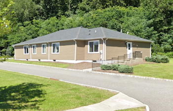 Exterior view of Hanover Respite Group Home with many green trees behind it