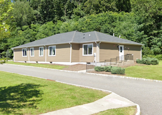 Exterior view of Hanover Respite Group Home with many green trees behind it