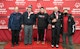 Four men in jackets stand on a podium with a fifth man on the side at a Special Olympics of NJ winter event.