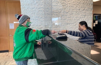 A man hands money to a teller inside a bank.