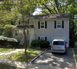 Exterior view of Morristown Group Home surrounded by trees, with a small tree in the front yard and a van parked in the driveway.